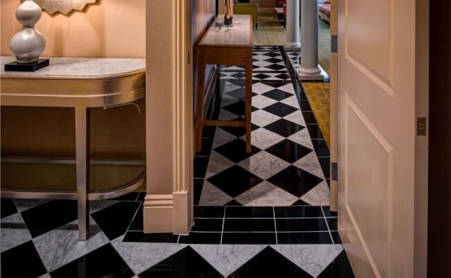 White and black tiled flooring with two tables decorated with a lamp and gold branches