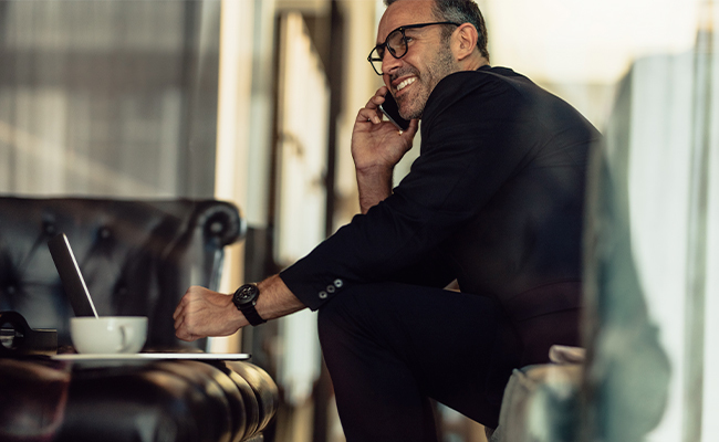 business man smiling and drinking coffee while on a business call