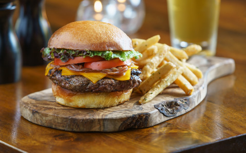 Burger and fries on a wood platter with beer