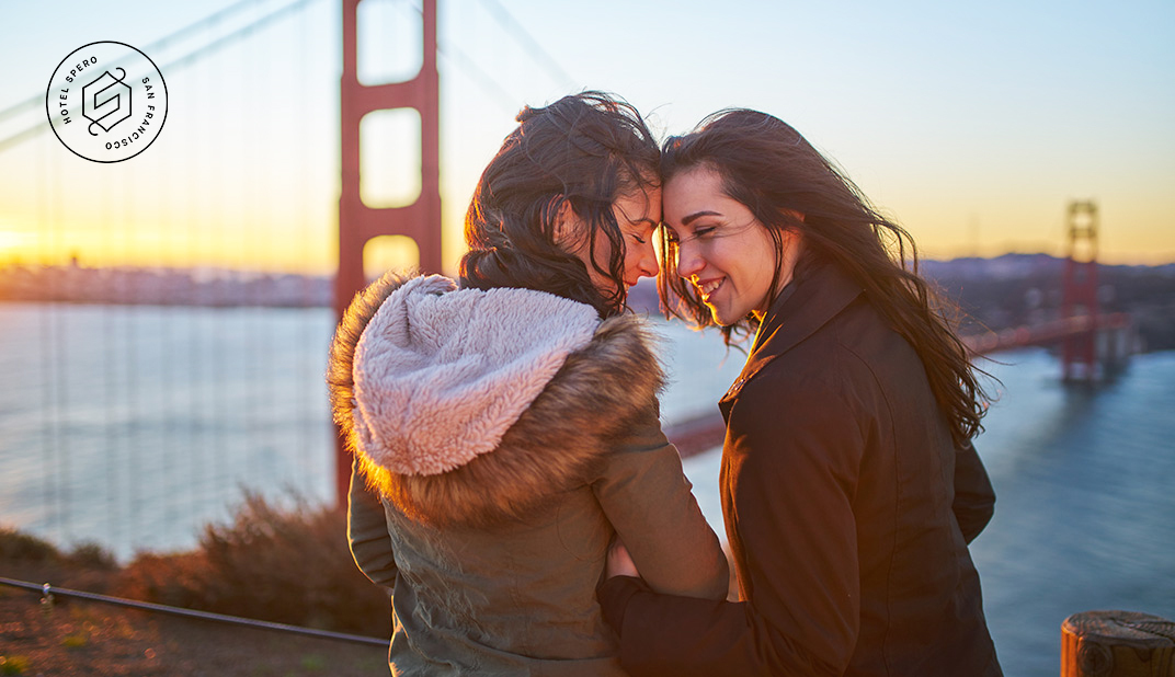 two women smiling at each other with the golden gate bridge in the background