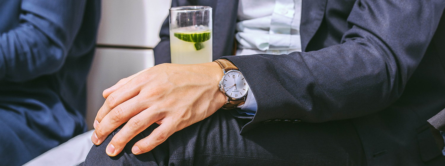 Body with a watch of a well dressed man and a green drink 