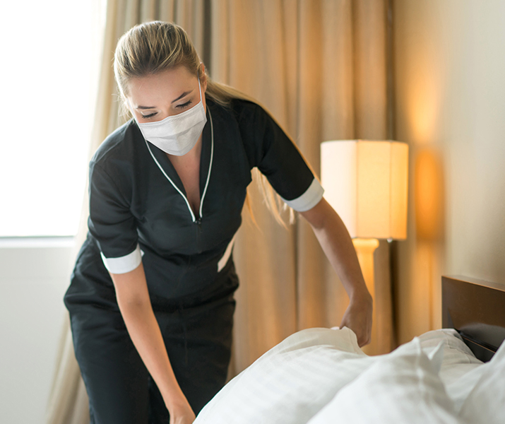 Woman from housekeeping making the bed 