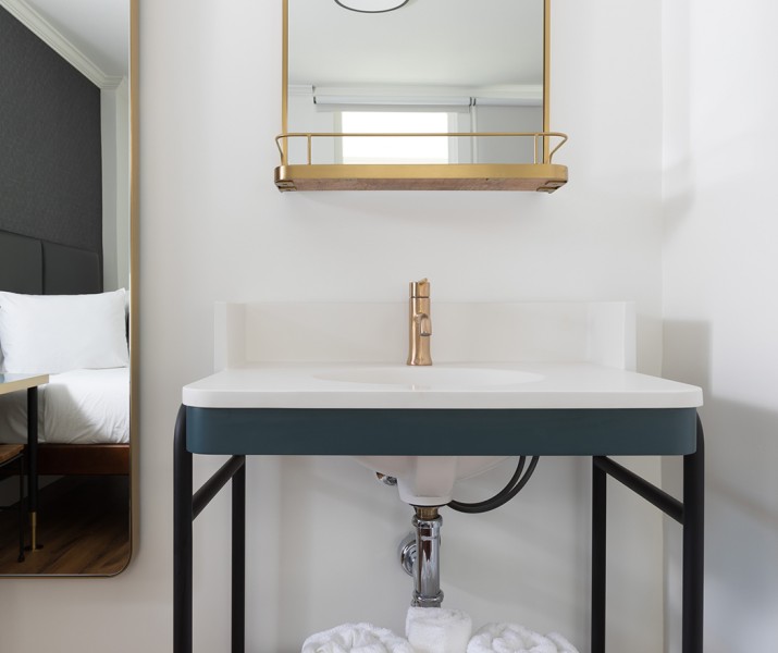 Stylish sink with four towels and a small and large golden mirrors 