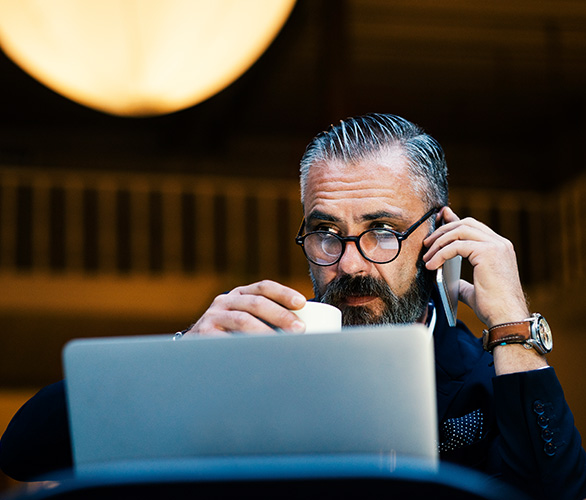 man on his cell phone with coffee cup & laptop