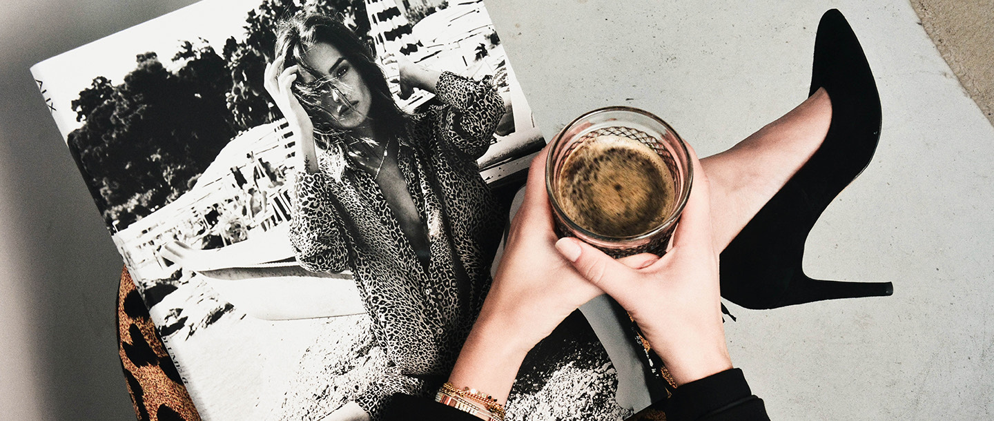 woman sitting with a magazine & a drink