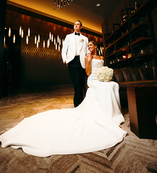 bride and groom posing with bride's long train in the forefront