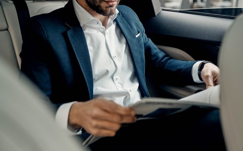 Closeup view of a young guy sitting in a car while he is having a look of newspaper