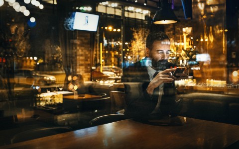 View of a  elderly well dressed guy in a empty restaurant checking his phone