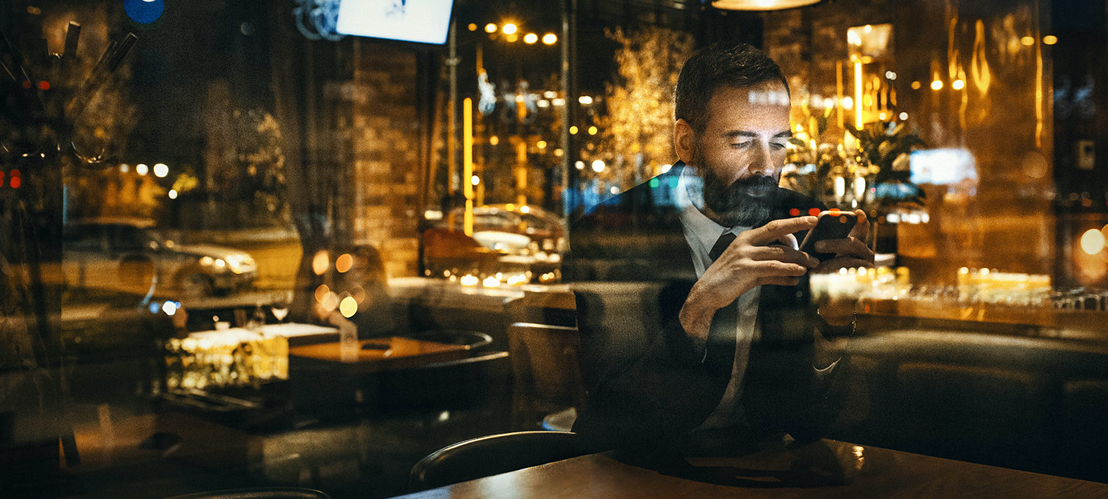 man looking at phone through window