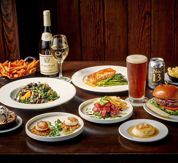 a view of a large wooden table filled with elegant dishes and wine and beer