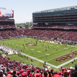49ers football game with the stands full, players on the field and cheerleaders cheering.