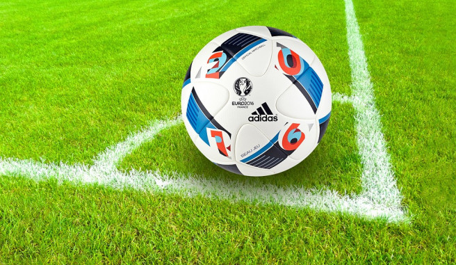 Adidas soccer ball from Euro 2016 on green grass with white chalk corner lines
