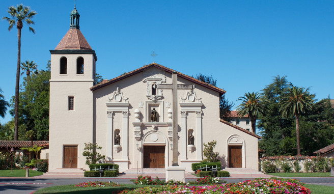 Mission Santa Clara de Asis with blue sky vibrant colorful flowers and palm trees