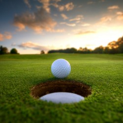 golf ball near hole with sunsetting