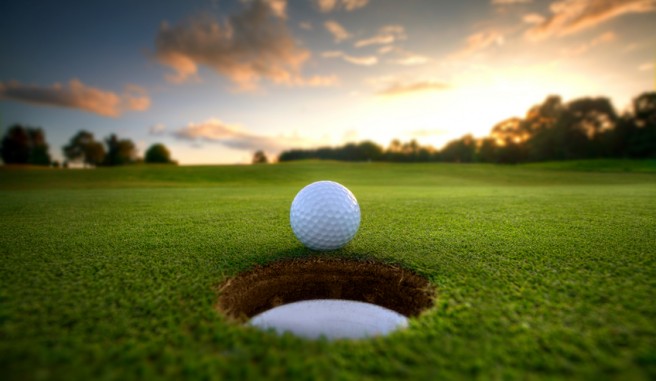 golf ball near hole with sunsetting