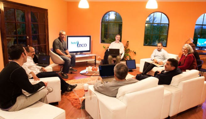 informal meeting space. group of people sitting in business center surrounding a television Header