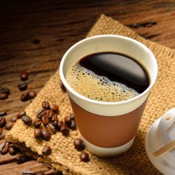 cup of coffee next to scattered coffee beans