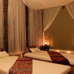 thai massage room contains draped lined walks. Warm dim lighting and exotic lined mats for a couples massage