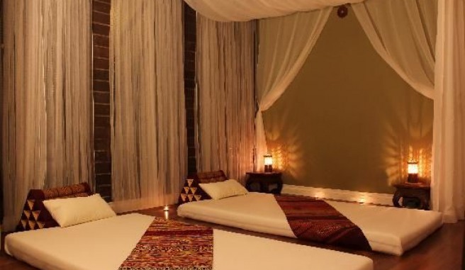 thai massage room contains draped lined walks. Warm dim lighting and exotic lined mats for a couples massage