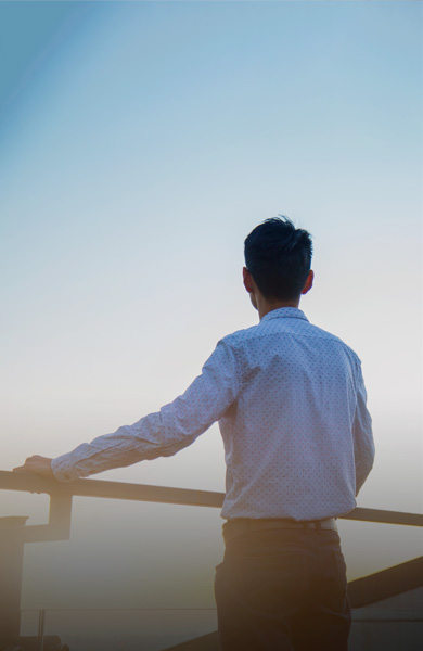 man in a suit looking out of his balcony to the horizon
