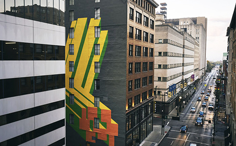 exterior of building with a yellow and green mural on the side of the building
