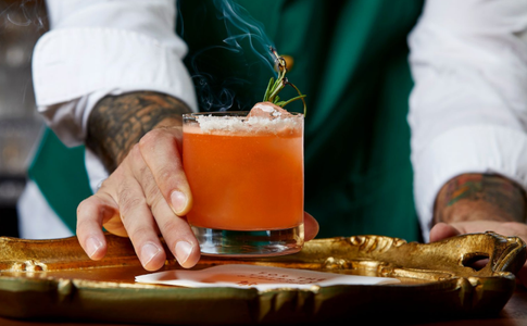 bartender holding out a cocktail on a plate