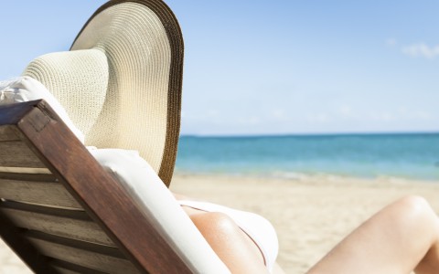 women tanning on beach wearing big hat