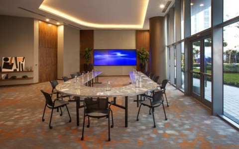 Caribbean Meeting Room has large u shaped table, large triple screen tv. ;large floor to ceiling windows and entrance to exterior
