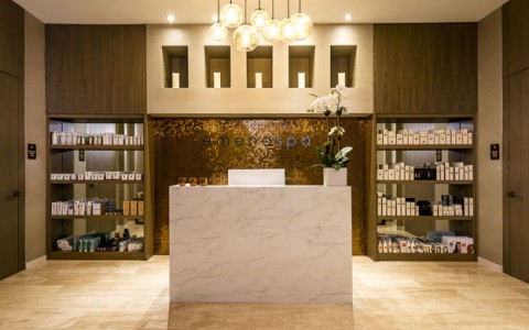 Emena Spa Lobby with large marble front desk with a wall of products displayed behind.