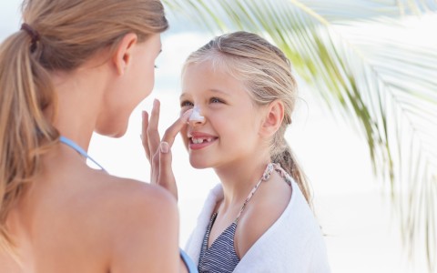Mom putting sunscreen on daughter's nose