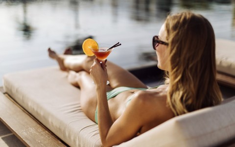 woman holding a drink on lounge chair by pool