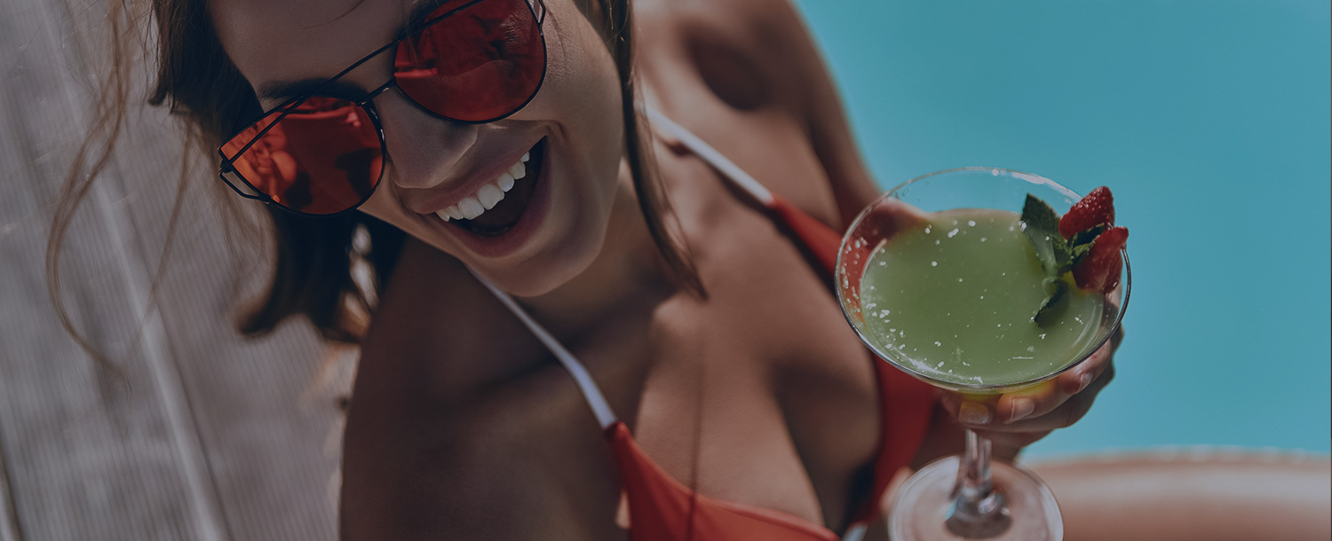 Woman next to pool with drink in hand