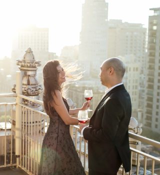 couple standing in the rooftop with glasses of wine