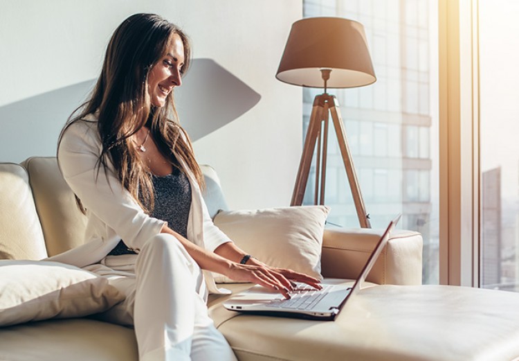 woman sitting on a couch working on her laptop