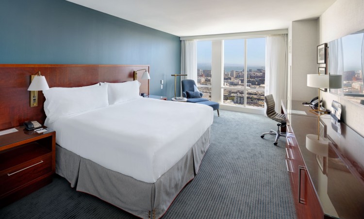 large room with a huge bed and a view of the city