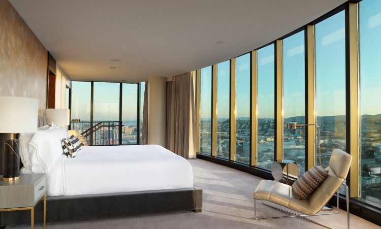 huge room with a large bed and a view of the city