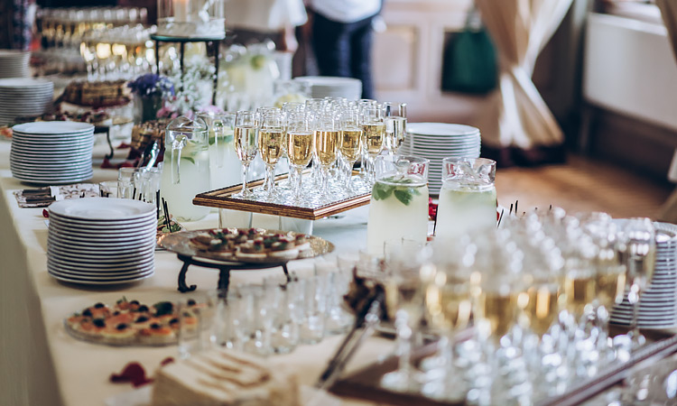 catering table filled with trays of champagne glasses and plates of appetizers