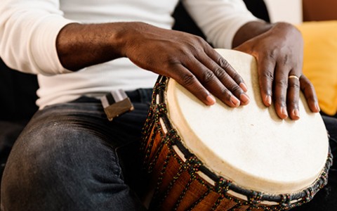 A male with his hands resting on a hand drum.