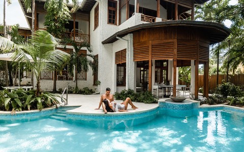 A male and female sitting next to the pool and villa.