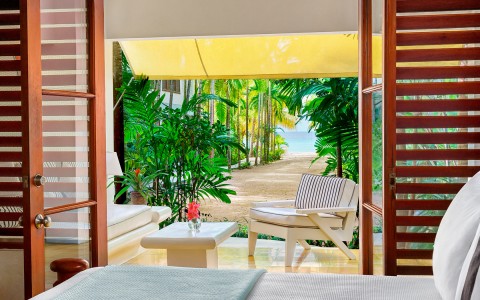 Outdoor patio with white sofa and chair under a bright yellow awning during the day.