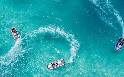 Three jet skis in the bright blue water during the day.