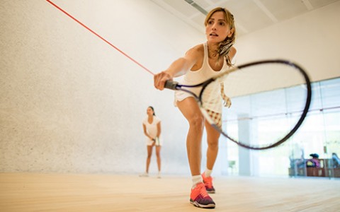 Female focusing on hitting tennis ball at indoor court.