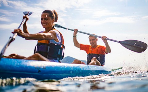 Smiling female and male kayaking in the daylight.