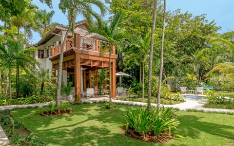Two story villa overlooking tall green palm trees and pool.
