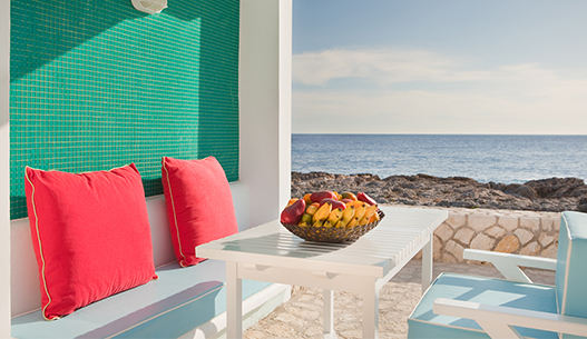 outside seating with a view of the ocean and a bowl of fruits