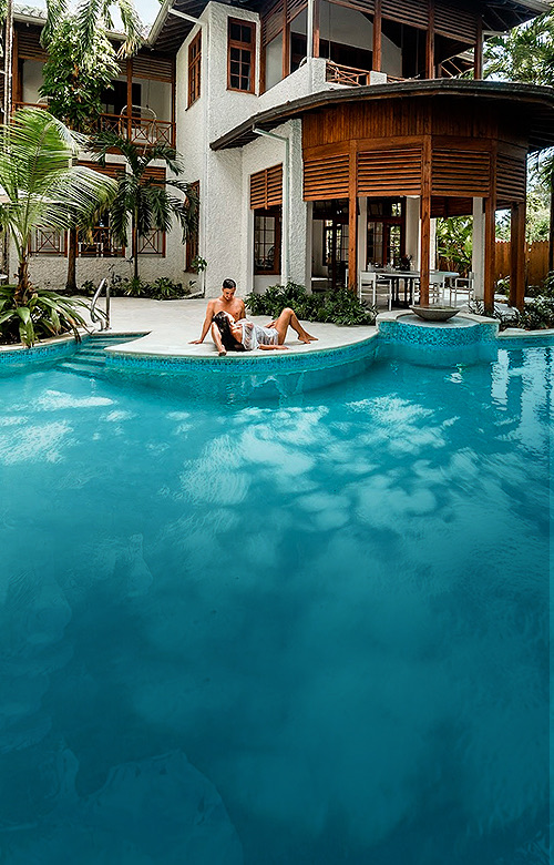 Couple sitting poolside near a villa.