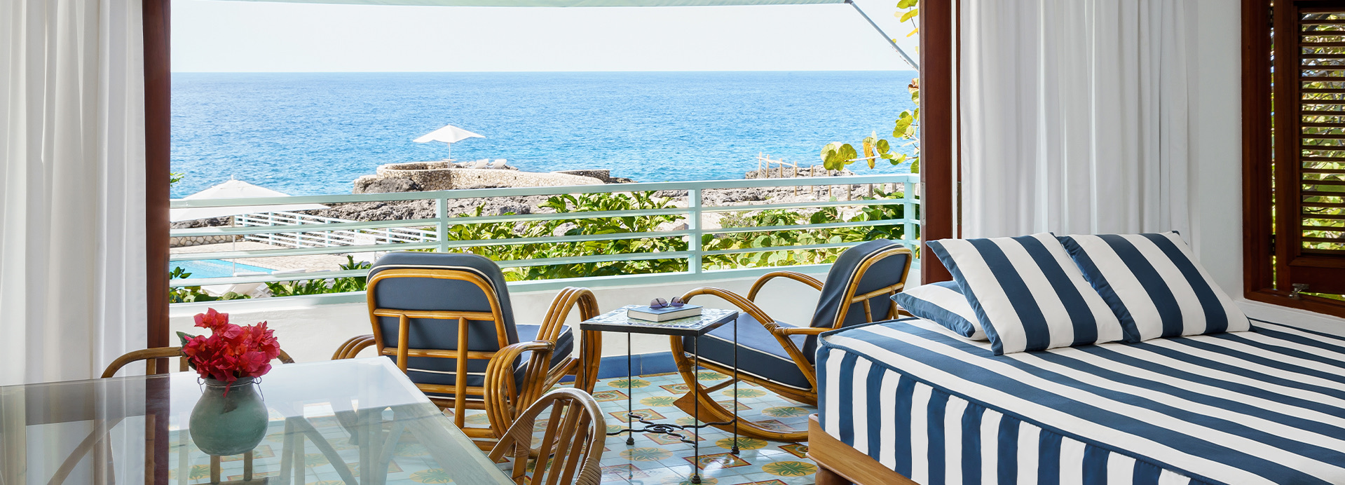 Two brown and blue chairs and a small table on the balcony overlooking the ocean view during the day.