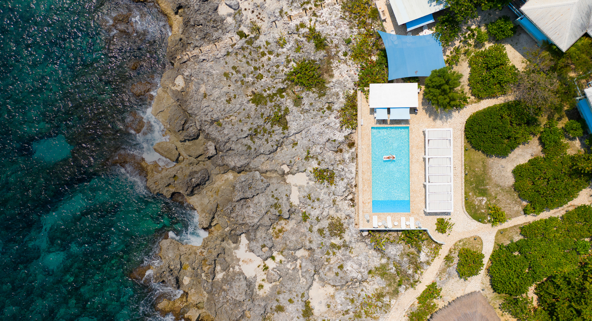 Aerial view of a crystal blue pool next to the ocean.