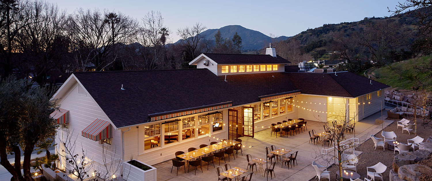 a patio dining area outside a white building lit up with lights at night
