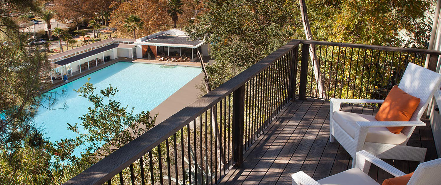 a large pool with small, antique looking pool buildings and a view of the mountains in the back
